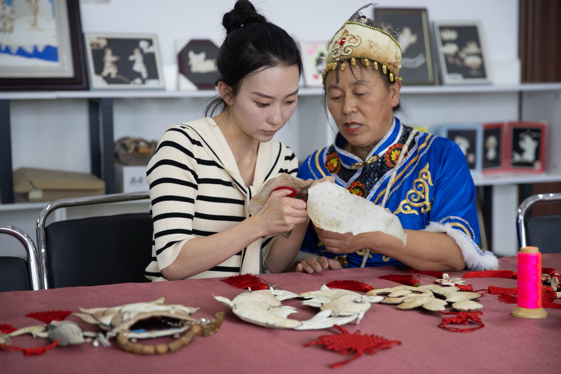 9月7日，在黑龍江撫遠市烏蘇鎮抓吉赫哲族村，尚美含（左）向魚皮制作技藝傳承人學習魚皮藝術品制作。新華社記者 張濤 攝