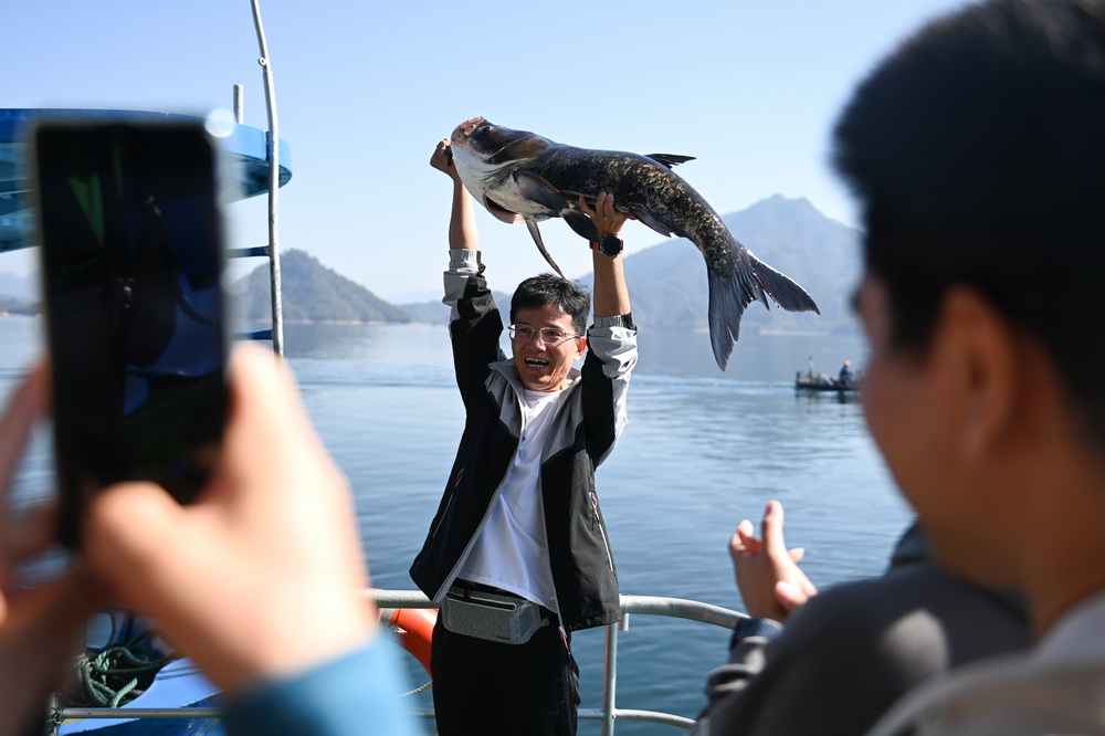 10月22日，在浙江省淳安縣千島湖黃山尖水域，游客用雙臂舉起剛捕獲的“魚王”。