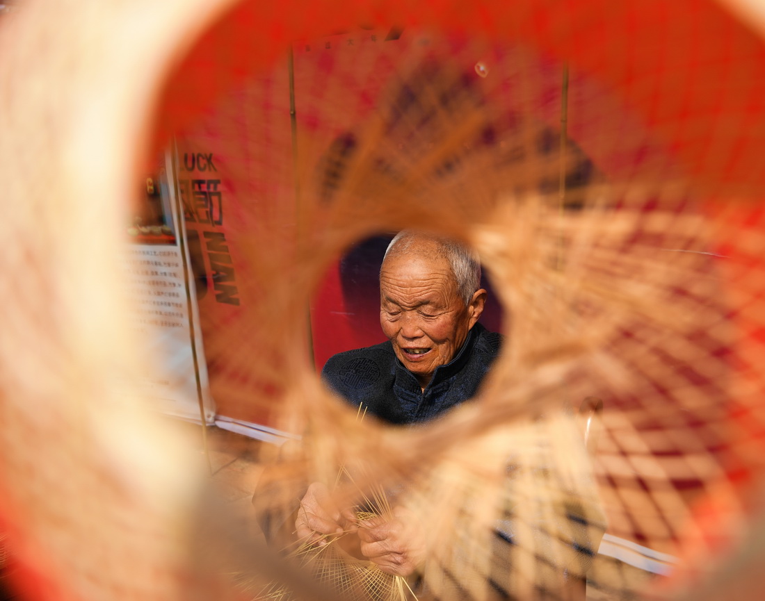 王学坤在西安市灞桥区白鹿原上的非遗基地展位编织竹篾灯笼（2月4日摄）。