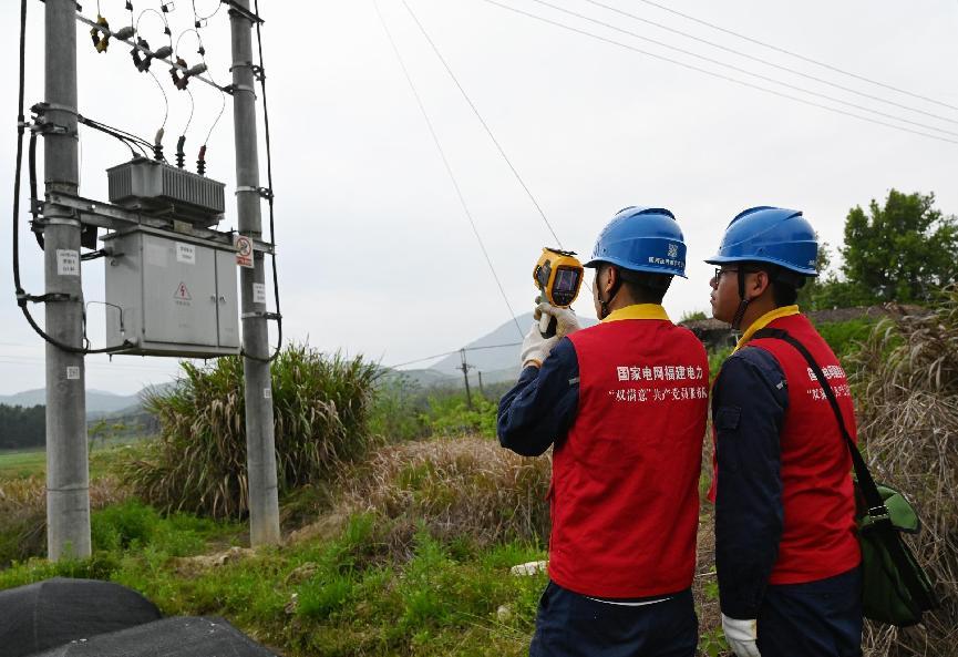 11月26日，福建南平邵武市供電公司和平鎮(zhèn)供電所員工唐智超、何守昌對(duì)10千伏河源線16桿設(shè)備進(jìn)行測(cè)溫。(朱麗）