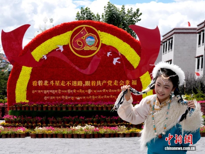 8月19日，隨著西藏自治區(qū)成立60周年慶?；顒优R近，拉薩氛圍濃。拉薩街頭，處處是張燈結(jié)彩的盛景，洋溢著一派祥和與歡騰的氛圍。圖為游客在拉薩大昭寺廣場上的大慶宣傳標(biāo)語前留念。中新社記者 李林 攝